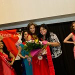 Amalia Gohn Awarding The Winner - Suzanne Perez with a bouquet of flowers and sash.